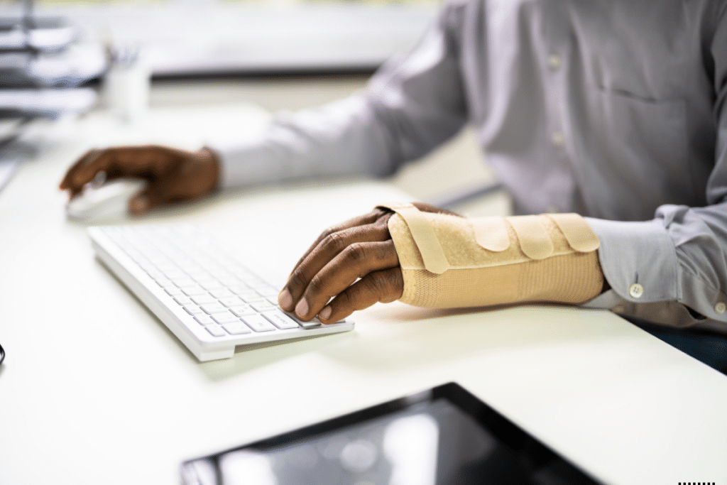 An man injured on one hand typing a computer with one hand